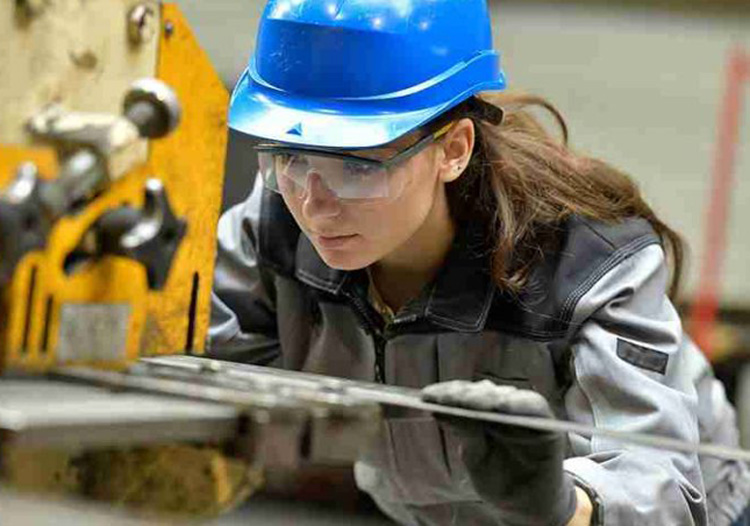 Young female wearing PPE undertaking engineering work