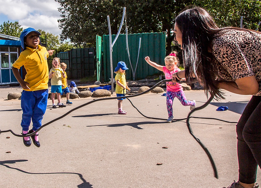 Children and teacher playing with a skipping rope