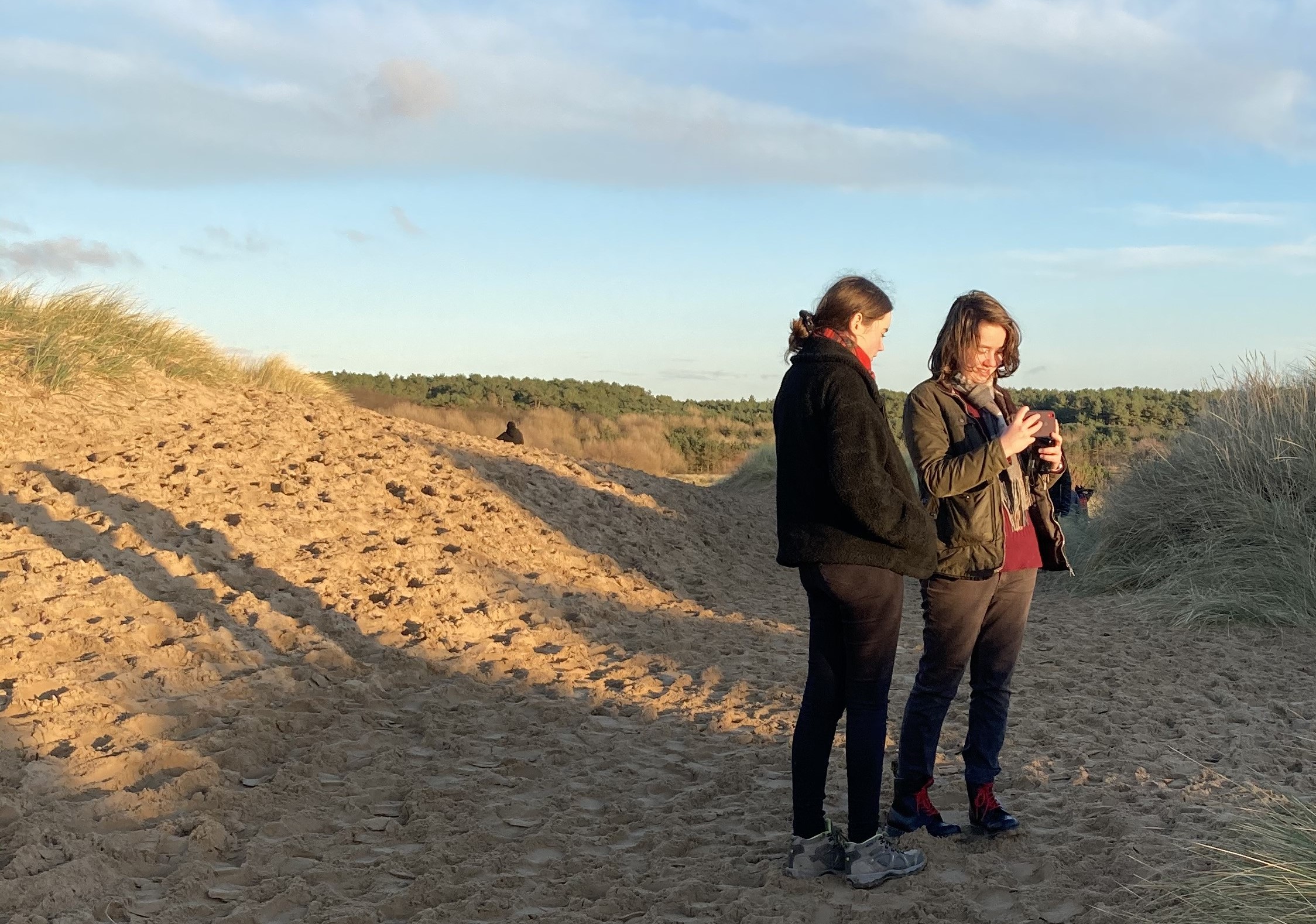 Two females using mobile devices in sandy area